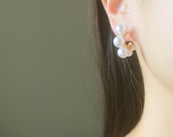 May include: A pair of gold-toned earrings with a cluster of white pearls. The earrings are designed to be worn on the upper lobe of the ear.
