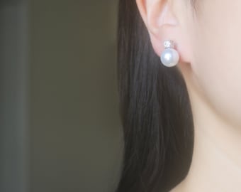 May include: A pair of pearl earrings with a small clear stone accent. The earrings are silver in color and have a classic design.