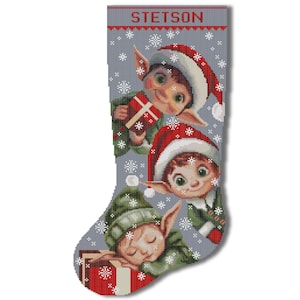 May include: A grey Christmas stocking with the name "STETSON" embroidered at the top. Three elves are depicted on the stocking, one holding a gift, one looking out, and one sleeping. The stocking is decorated with snowflakes.