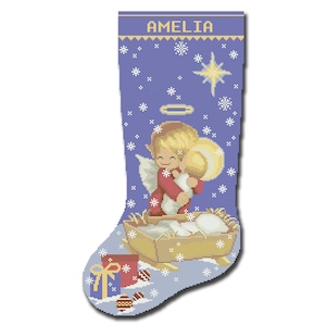 Op de afbeelding: Een blauwe kerstsok met een wit sneeuwvlokkenpatroon. De sok heeft een scène van een engel die een baby in een kribbe vasthoudt. De sok is gepersonaliseerd met de naam "AMELIA".