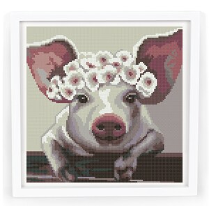 May include: A white pig with pink ears wearing a white flower crown. The pig is looking directly at the viewer and has a gentle expression.