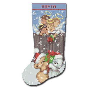 May include: A Christmas stocking with a blue background and snowflakes. The stocking has the name "SOFIA" at the top. Three angels are peeking over a wooden fence, and a teddy bear is holding a gift.