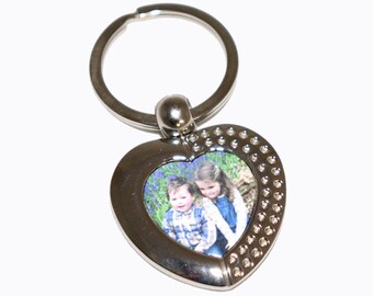 May include: Silver heart-shaped photo keychain with a picture of two children. The keychain has a silver ring for attaching to keys.