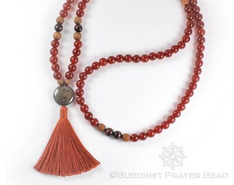 May include: A red carnelian mala with a brown tassel and a dark brown stone bead. The mala is made of 108 beads and is used for meditation and prayer.
