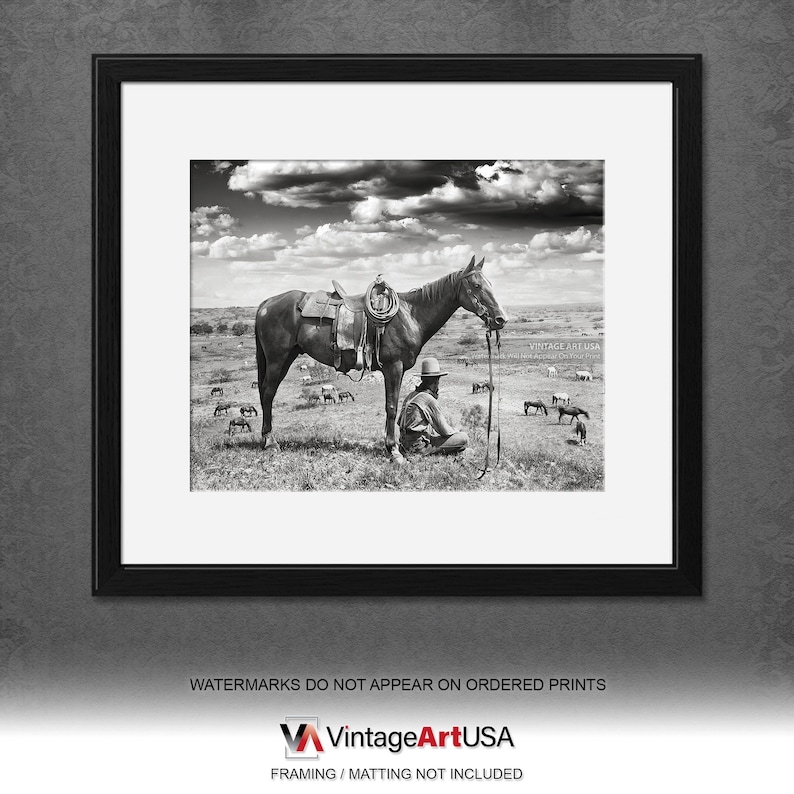 Puede incluir: Una fotograf&iacute;a en blanco y negro de un vaquero sentado en el suelo junto a un caballo. El vaquero lleva un sombrero y sostiene una cuerda. El caballo lleva una silla de montar y una brida. Hay otros caballos en el fondo.