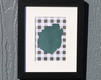 May include: A black framed picture with a white mat and a black and white checkered background. A teal blue shape is cut out of the checkered background.