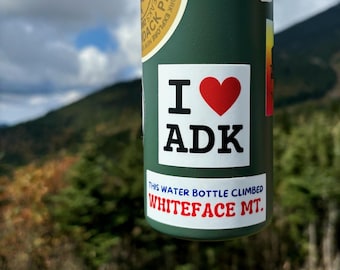 May include: A green water bottle with a sticker that says "I love ADK" and a red heart. The bottle also has a sticker that says "This water bottle climbed Whiteface Mt."