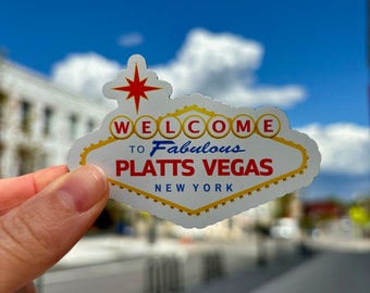 May include: A white and yellow Vegas-style sign with a red star on top. The sign says "Welcome to Fabulous Platts Vegas, New York".