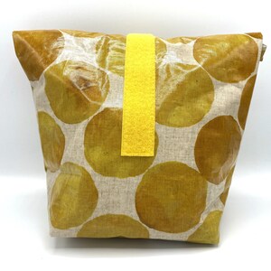 Könnte beinhalten: Eine gelbe und braune Tragetasche mit einem gelben Stoffgriff. Die Tasche ist aus Leinenstoff und hat ein Muster aus gelben Kreisen auf braunem Hintergrund.