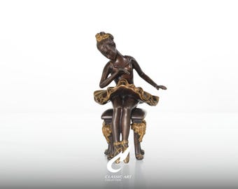 Escultura de bailarina em bronze, cabeça inclinada em pose de repouso, estatueta dourada para banco barroco.