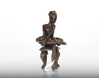 Escultura de bailarina em bronze, com os braços cruzados em pose contemplativa, estatueta de banco barroco dourada.