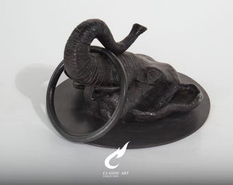 Escultura de cabeça de elefante em latão, com tromba levantada e anel, ornamento de mesa quase preto.