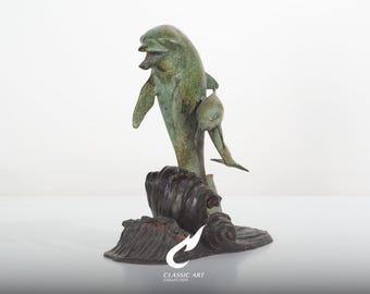 Escultura de golfinho em latão, mãe e filhote sobre base ondulada, decoração náutica para o dia a dia.