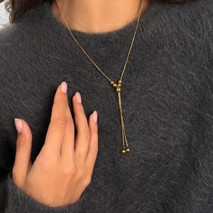 A Gold Lariat Necklace (Bolo Necklace) featuring an Adjustable Necklace slider. This Non Tarnish Jewelry set includes matching Small Hoop Earrings.