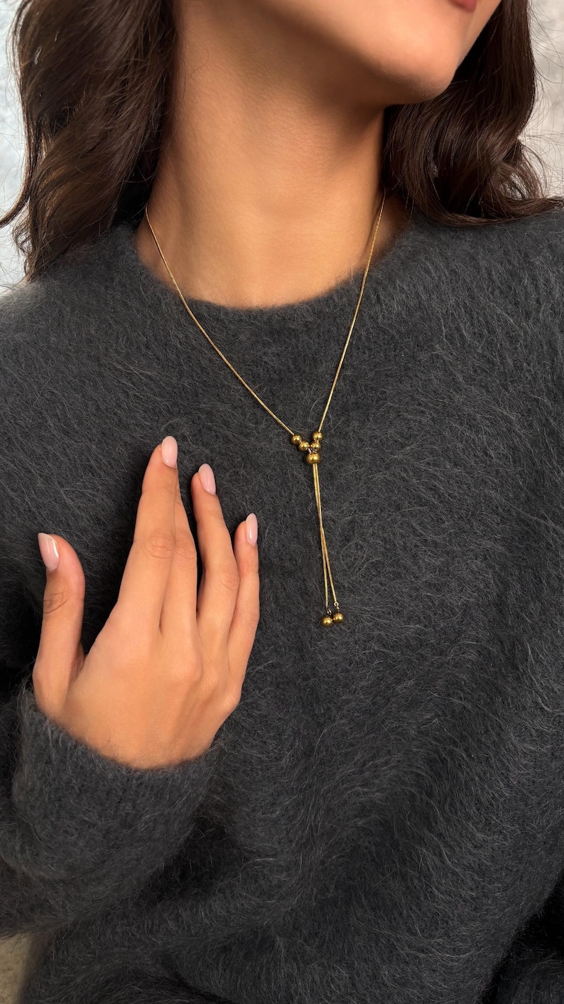 A Gold Lariat Necklace (Bolo Necklace) featuring an Adjustable Necklace slider. This Non Tarnish Jewelry set includes matching Small Hoop Earrings.