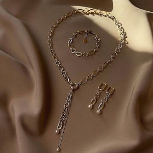 Conjunto de joyas con cadena de oro llamativa, collar en forma de Y y pendientes largos.