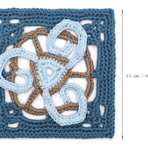 Puede incluir: Una pieza cuadrada de ganchillo hecha a mano con un diseño central en azul claro y marrón, rodeada por un borde azul oscuro. La pieza mide 11 cm (4,33 pulgadas) de lado. El diseño incluye patrones arremolinados y un motivo central floral.