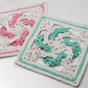 Puede incluir: Dos cuadrados tejidos a crochet, uno en blanco con un diseño turquesa y otro en blanco con un diseño rosa.