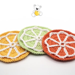 May include: Three crocheted coasters in the shape of orange slices. The coasters are yellow, green, and orange with white stitching.