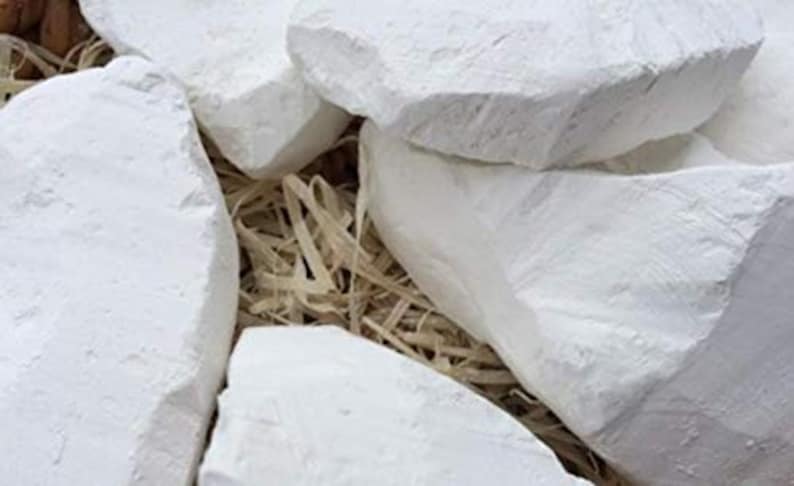 May include: White chalk rocks in a pile, with a natural, rough texture. The rocks are arranged in a basket filled with straw.