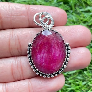 Op de afbeelding: Een zilveren hanger met een grote, ovale, roze edelsteen die in een zilveren bezel is gezet. De hanger heeft een zilveren bail om aan een ketting te bevestigen.