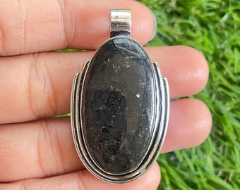 May include: A silver pendant with a black oval gemstone. The pendant has a smooth, polished finish and a simple design.