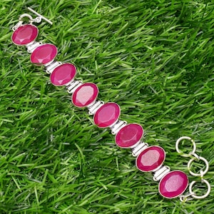 May include: A silver bracelet with pink oval gemstones. The bracelet has a toggle clasp.