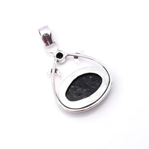 Pu&ograve; includere: Ciondolo in argento con una pietra nera incastonata in una cornice a forma di lacrima. La cornice presenta un design decorativo con piccole lune crescenti.