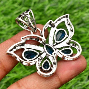 May include: Silver butterfly pendant with blue gemstone accents. The pendant has a filigree design and is marked "925" on the back.