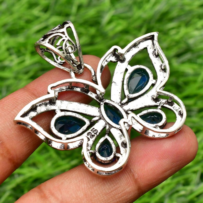 May include: Silver butterfly pendant with blue gemstone accents. The pendant has a filigree design and is marked "925" on the back.