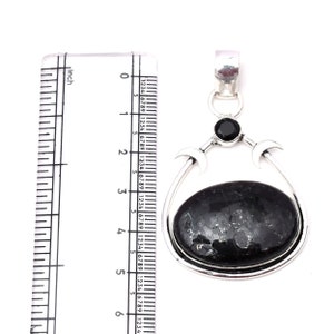 Pu&ograve; includere: Un ciondolo d'argento con una pietra ovale nera e un design a tripla luna. Il ciondolo misura circa 5 cm di lunghezza.