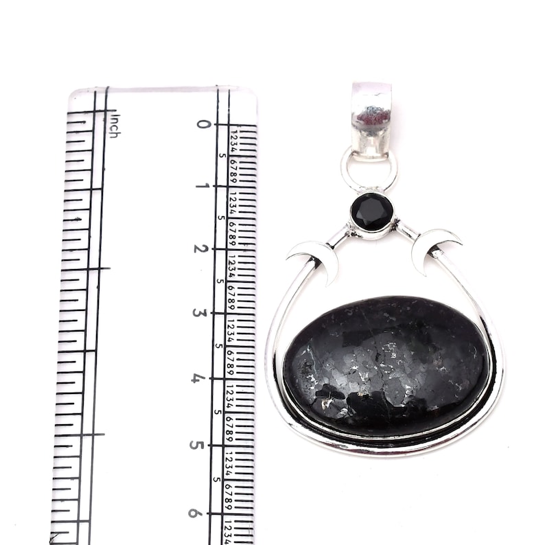 Pu&ograve; includere: Un ciondolo d'argento con una pietra ovale nera e un design a tripla luna. Il ciondolo misura circa 5 cm di lunghezza.