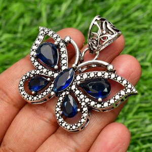 May include: Silver butterfly pendant with blue gemstone accents. The pendant features intricate details and a delicate design.