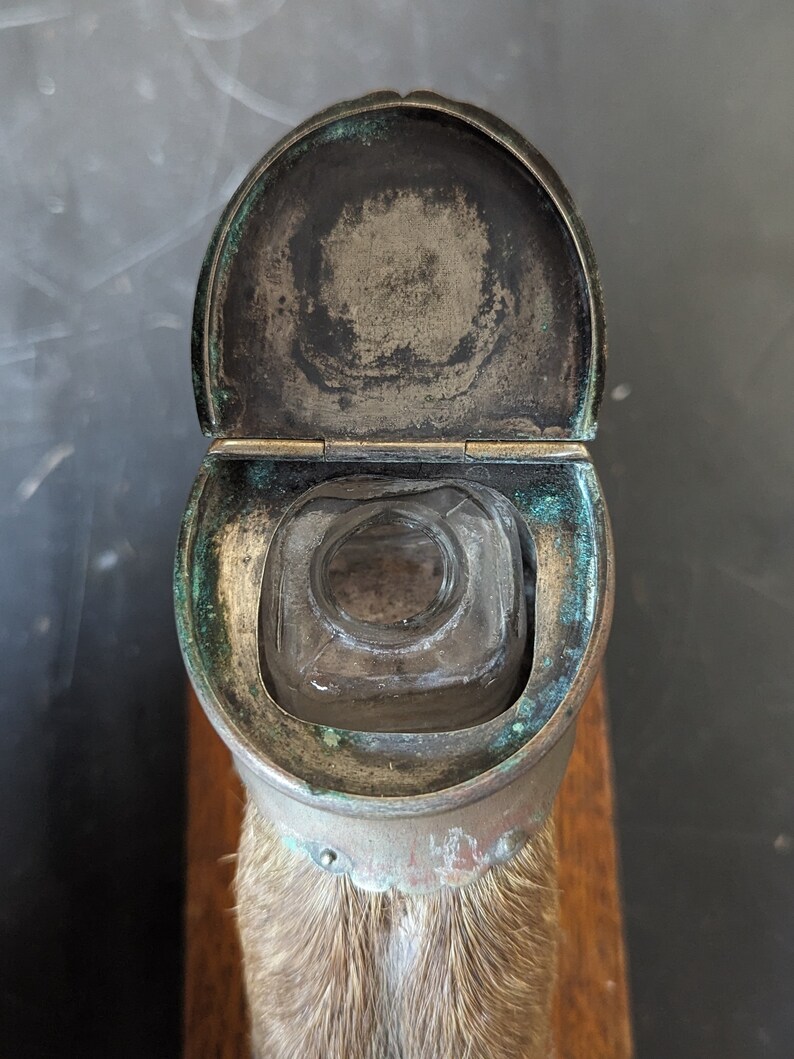 May include: A vintage glass inkwell with a hinged lid, made of brass and mounted on a piece of animal fur.