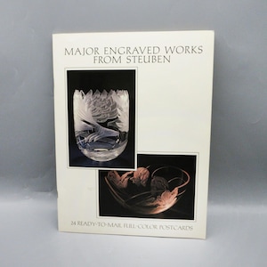 May include: A postcard set featuring engraved glass artwork from Steuben. The cover displays two examples of the artwork, including a detailed glass bowl with a bird design. The text reads "MAJOR ENGRAVED WORKS FROM STEUBEN" and "24 READY-TO-MAIL FULL-COLOR POSTCARDS."