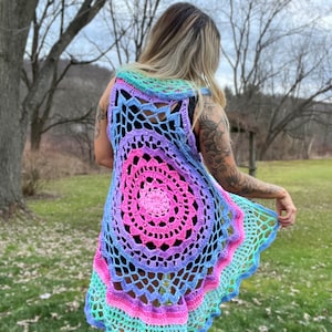 May include: A rainbow crochet vest with a large circular design in the back. The vest is sleeveless and has a scalloped hem.