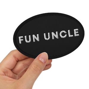 May include: A black oval patch with white embroidered text that reads "FUN UNCLE".