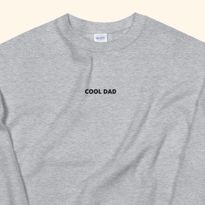 May include: A gray long-sleeved sweatshirt with the text "COOL DAD" embroidered on the front.