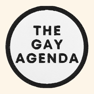 Może przedstawiać: Haftowana naszywka z napisem "THE GAY AGENDA" w kolorze czarnym, umieszczonym na białym okręgu. Okrąg obwiedziony jest grubą, czarną obwódką. Idealna do odzieży lub akcesoriów.