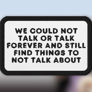 May include: Black and white embroidered patch with the text "WE COULD NOT TALK OR TALK FOREVER AND STILL FIND THINGS TO NOT TALK ABOUT".