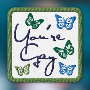 May include: An embroidered patch with the text "You're Gay" and five butterflies. Two butterflies are blue, and three are green.