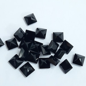 May include: A group of black square pyramid-shaped rhinestones.