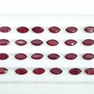 May include: Twenty maroon marquise-shaped gemstones arranged in four rows on a white surface. The gemstones are all the same size and shape. The text "Stonehubdesigns" is printed in black at the bottom of the image.