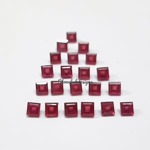 Könnte beinhalten: Eine Sammlung von 20 quadratischen Rubin-Edelsteinen. Die Edelsteine sind in einem dreieckigen Muster auf einer weißen Oberfläche angeordnet. Der Text "Stonehubdesigns" ist in der Mitte des Bildes sichtbar.