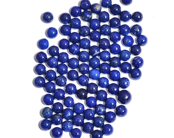 May include: A large group of round, dark blue lapis lazuli beads. The beads are scattered on a white background.