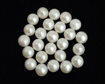 May include: A collection of 20 white pearl beads, arranged in a circular pattern on a black background.