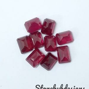 Può includere: Un gruppo di nove cabochon di pietre preziose rosse, tagliate a forma rettangolare, con una finitura lucida. Le pietre preziose sono disposte in un gruppo sciolto su uno sfondo bianco.