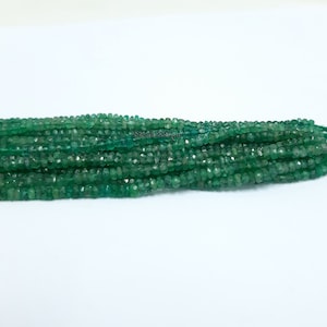 May include: A strand of green gemstone beads. The beads are faceted and have a slightly irregular shape. The beads are strung on a clear thread.