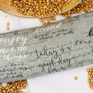 May include: Gray fabric pillow with white and black text that reads "blessed home is who you share it with", "enjoy the little things", "today is a love good day live for a", and "blessed family is the greatest gift".