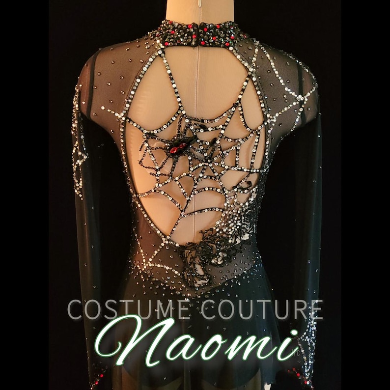 Puede incluir: Traje negro de manga larga con dise&ntilde;o de telara&ntilde;a en la espalda. El traje est&aacute; adornado con pedrer&iacute;a y presenta un cuello alto con detalles rojos. El texto "COSTUME COUTURE Naomi" es visible.